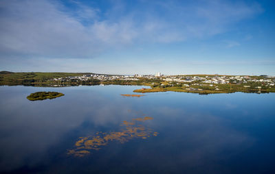 Beautiful peaceful landscape with city located along shoreline of tranquil river under blue sky