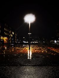 Wet illuminated street light in city at night