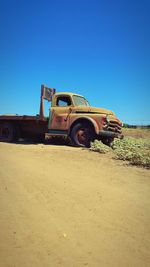 Vintage car on field against clear blue sky