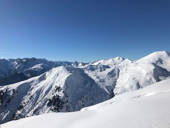 Scenic view of snowcapped mountains against clear blue sky