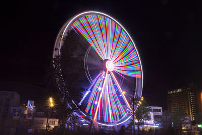 Low angle view of illuminated ferris wheel against clear sky at night