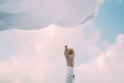 Low angle view of person hand against sky