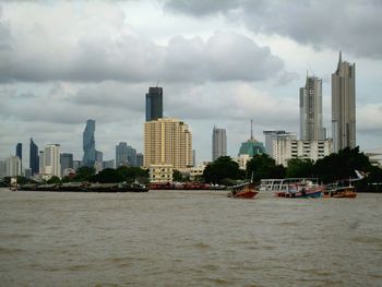 Sea by modern buildings against sky in city