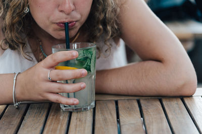 Midsection of woman having drink while sitting at table