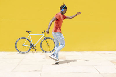 Energetic ethnic guy jumping near bicycle