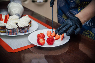 Midsection of man holding strawberries in plate on table