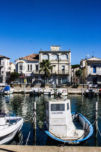 Boats moored in water against clear blue sky