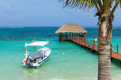 Boat moored by gazebo at sea against sky