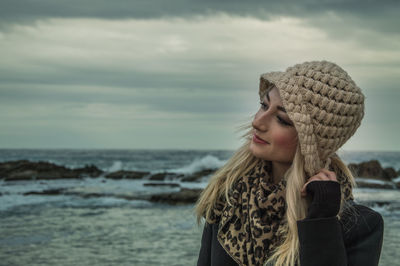 Portrait of woman by sea against sky during winter