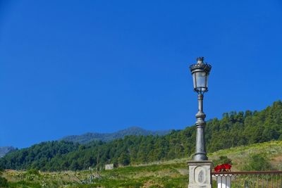 Street light by mountains against clear blue sky