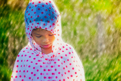 Girl wearing raincoat standing in park during rainfall