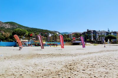 People on beach against clear blue sky