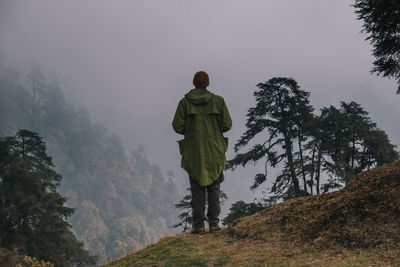 Rear view of man standing on mountain against sky