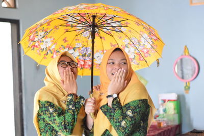 Women in hijab holding umbrella at home