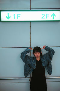 Portrait of woman standing against wall