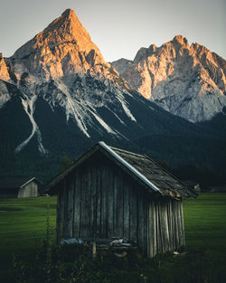 Log cabin on field against mountains