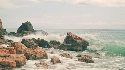 Scenic view of rocks in sea against sky