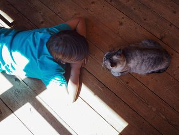 High angle view of boy with cat on hardwood floor