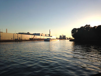 Silhouette of harbor by river against clear sky