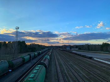 Train on railroad tracks against sky during sunset