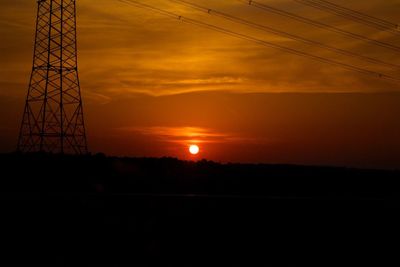 Silhouette of electricity pylon at sunset