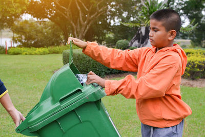 Side view of boy cleaning park