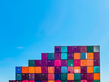 Stack of multi colored pier against blue sky