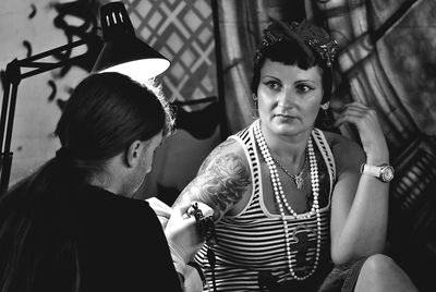 Artist making tattoo on woman hand