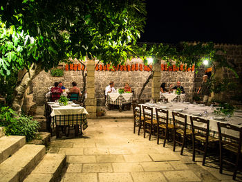 Empty chairs and table against trees at night