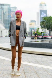 Full length portrait of young woman standing in city