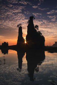 Silhouette built structure in lake against sky during sunset