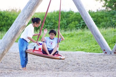Young woman with boy playing on swing at playground