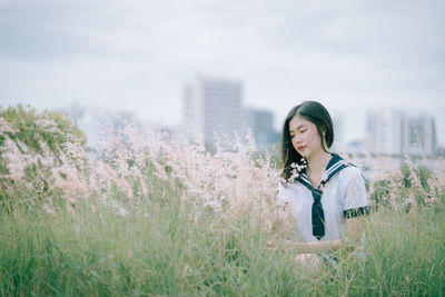 Young woman sitting amidst plants on field