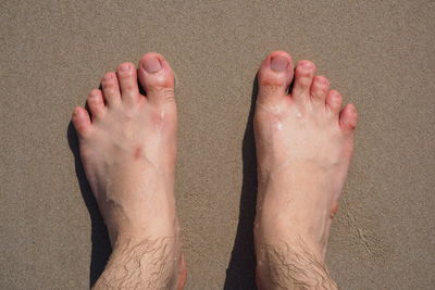 Low section of man standing at beach