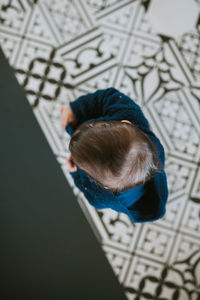 High angle view of baby girl standing on tiled floor at home