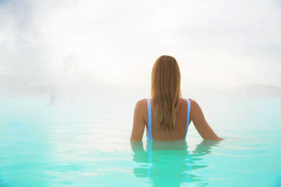 Rear view of woman in hot spring during foggy weather