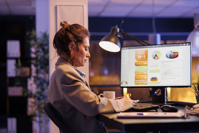 Side view of young woman working at home