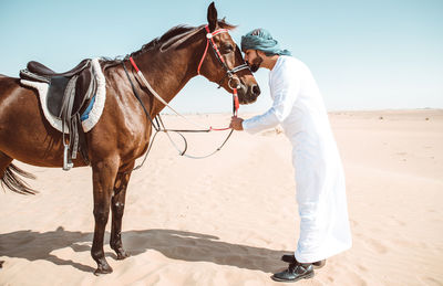 View of person riding horse on sand