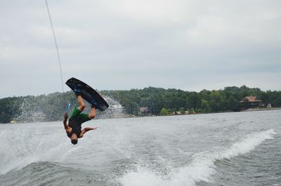 Man wakeboarding on sea against cloudy sky