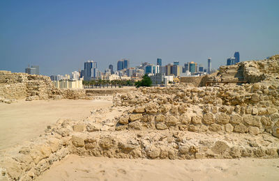 Bahrain fort structure ruins with manama modern cityscape in the backdrop, bahrain