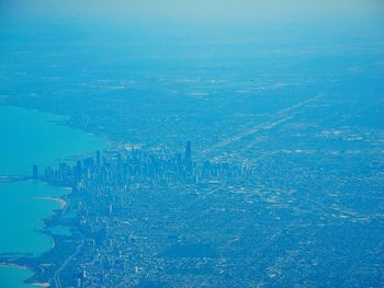 Aerial view of cityscape by sea against blue sky