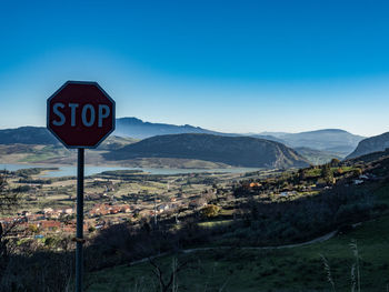 Road sign by mountains against blue sky