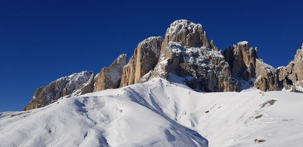 Low angle view of snowcapped mountain against clear blue sky