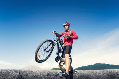 Man riding bicycle on mountain against sky