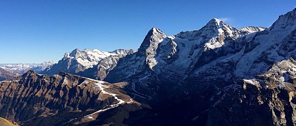 Scenic view of snowcapped mountains against clear blue sky