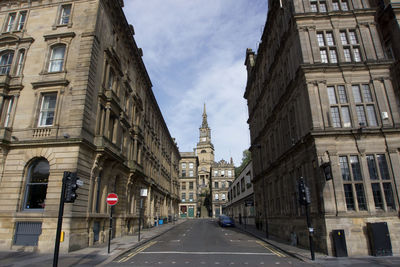 Road amidst buildings in city against sky