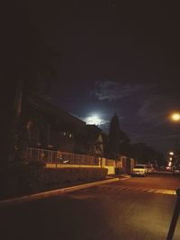 Illuminated road against sky at night