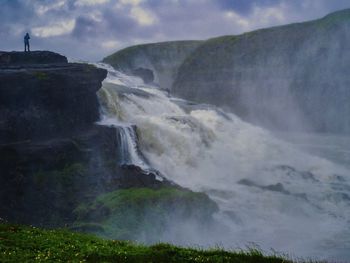 Scenic view of waterfall against sky