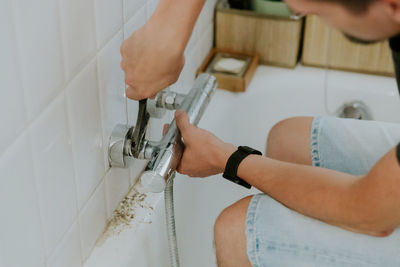 A young man installs a faucet in the bathroom.