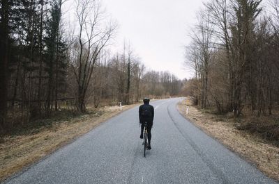 Rear view of man riding bicycle on road